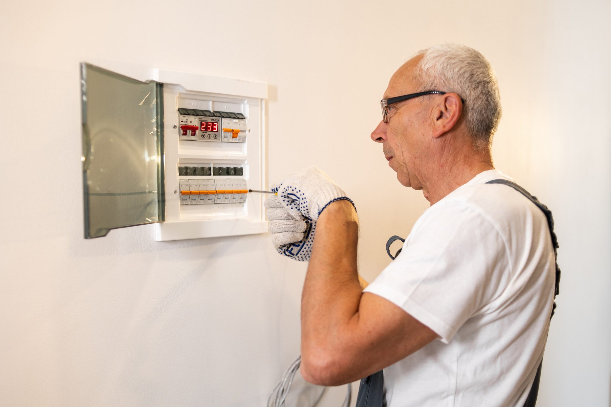 Elettricista controlla salvavita e magnetotermici in un quadro elettrico domestico.
